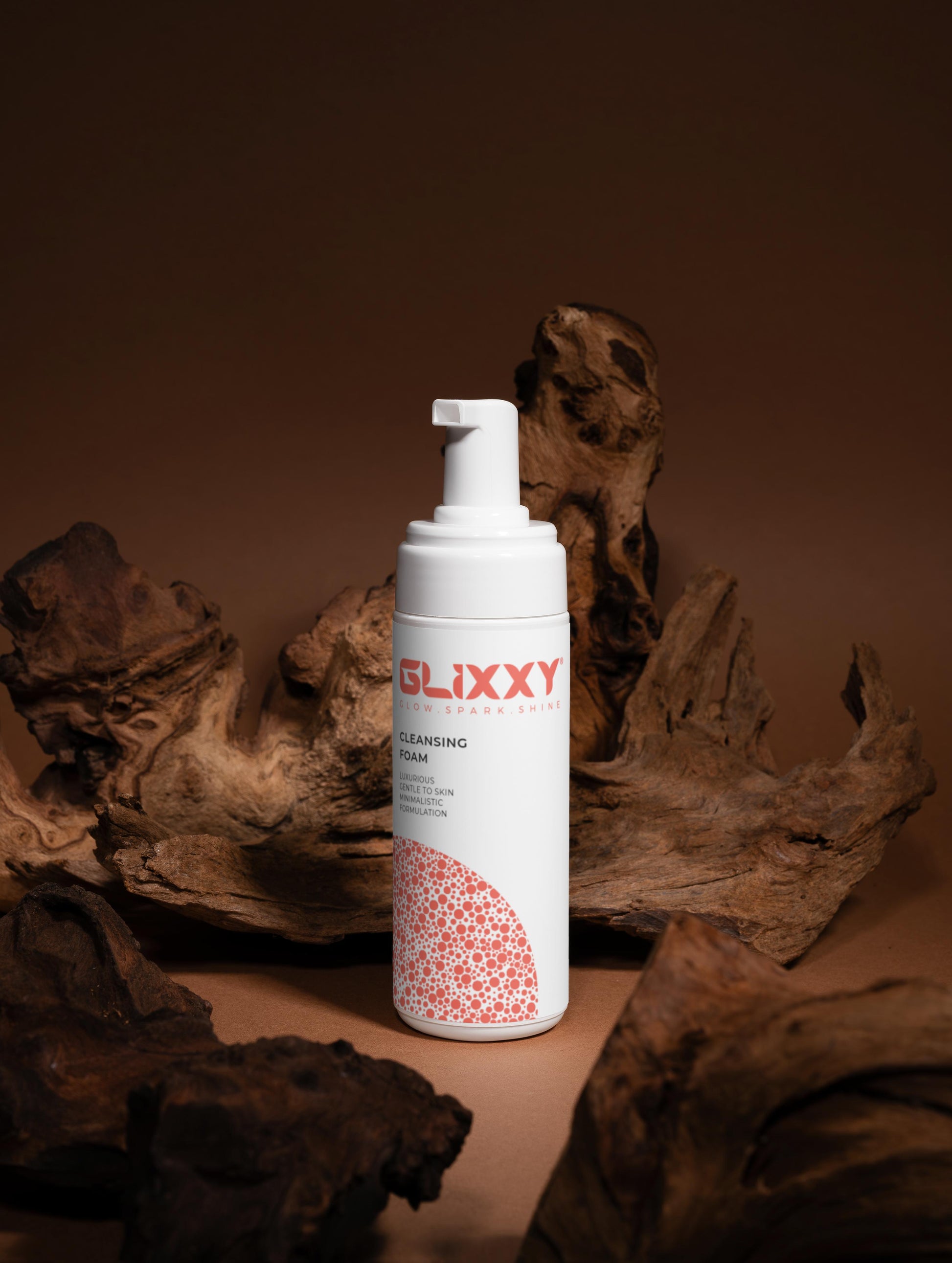 Glixxy cleansing foam bottle with pump on a brown background