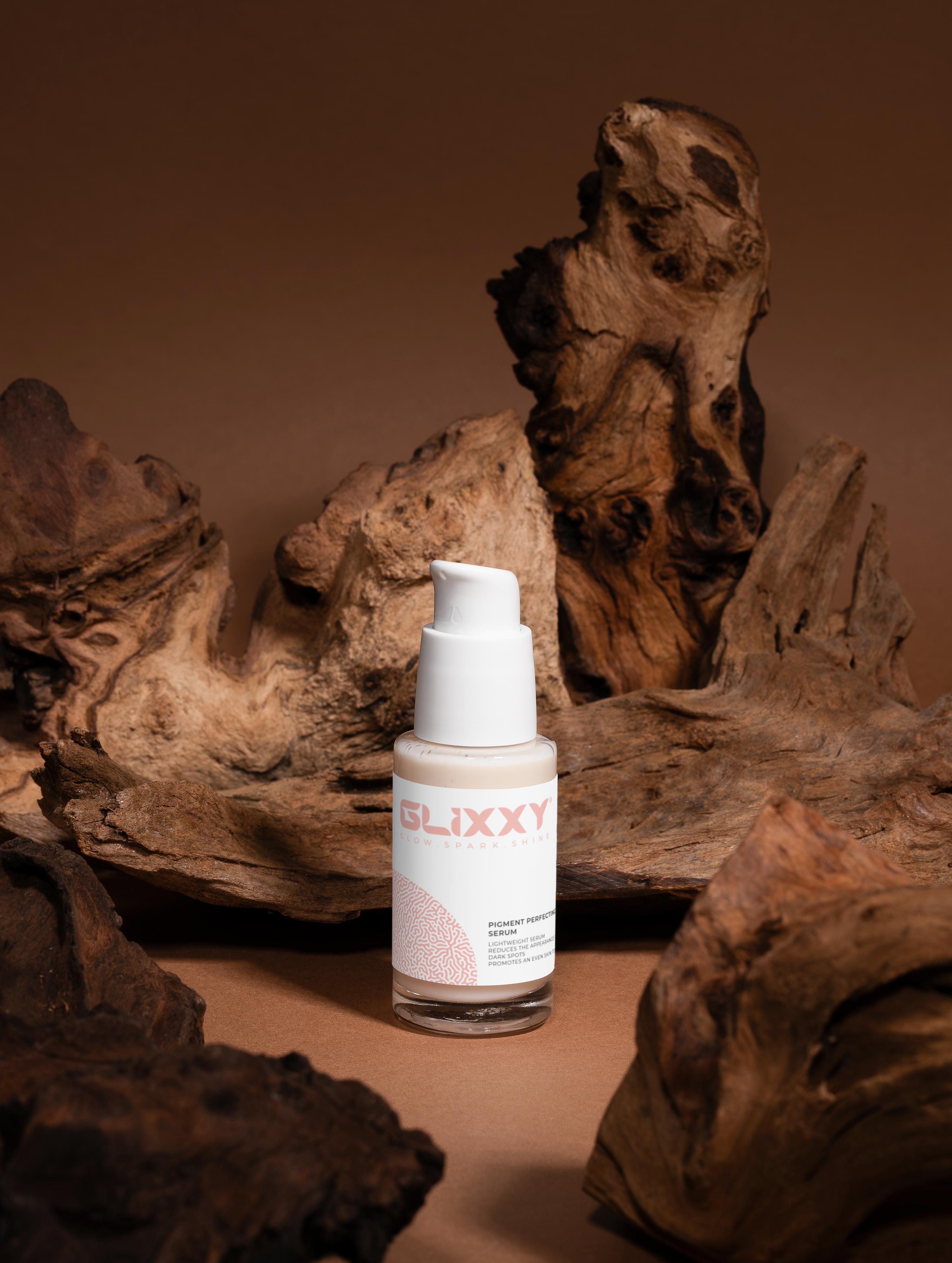 Skincare bottle labeled 'Glixxy' on a brown background with natural wood elements