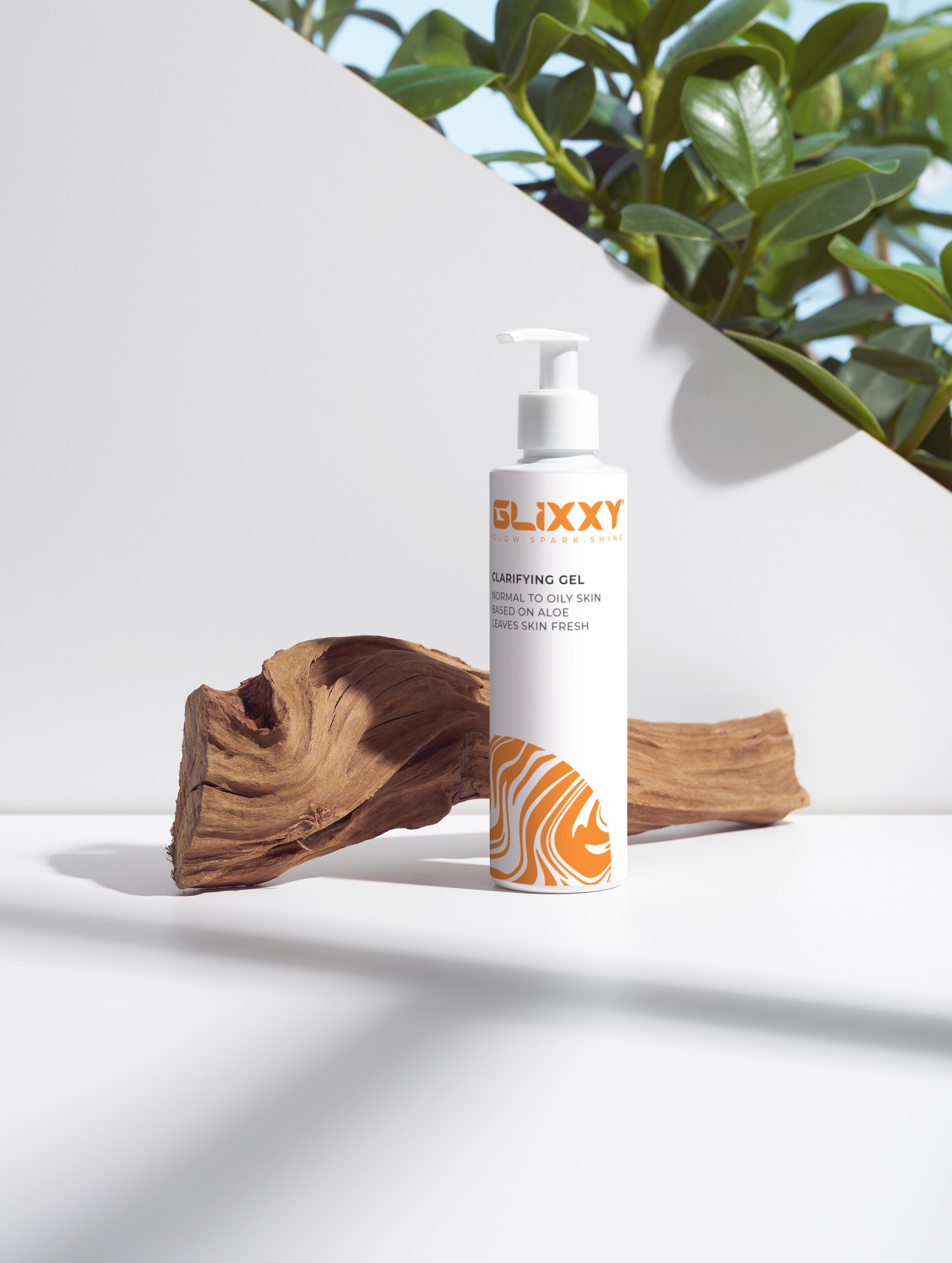 Glixxy clarifying gel bottle on a white surface with natural elements