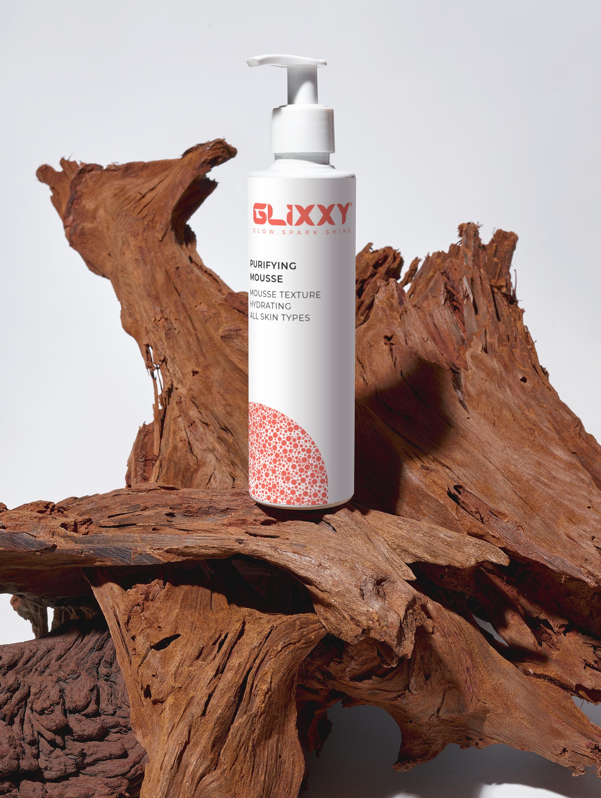 Glixxy purifying mousse bottle on a wooden surface with a white background