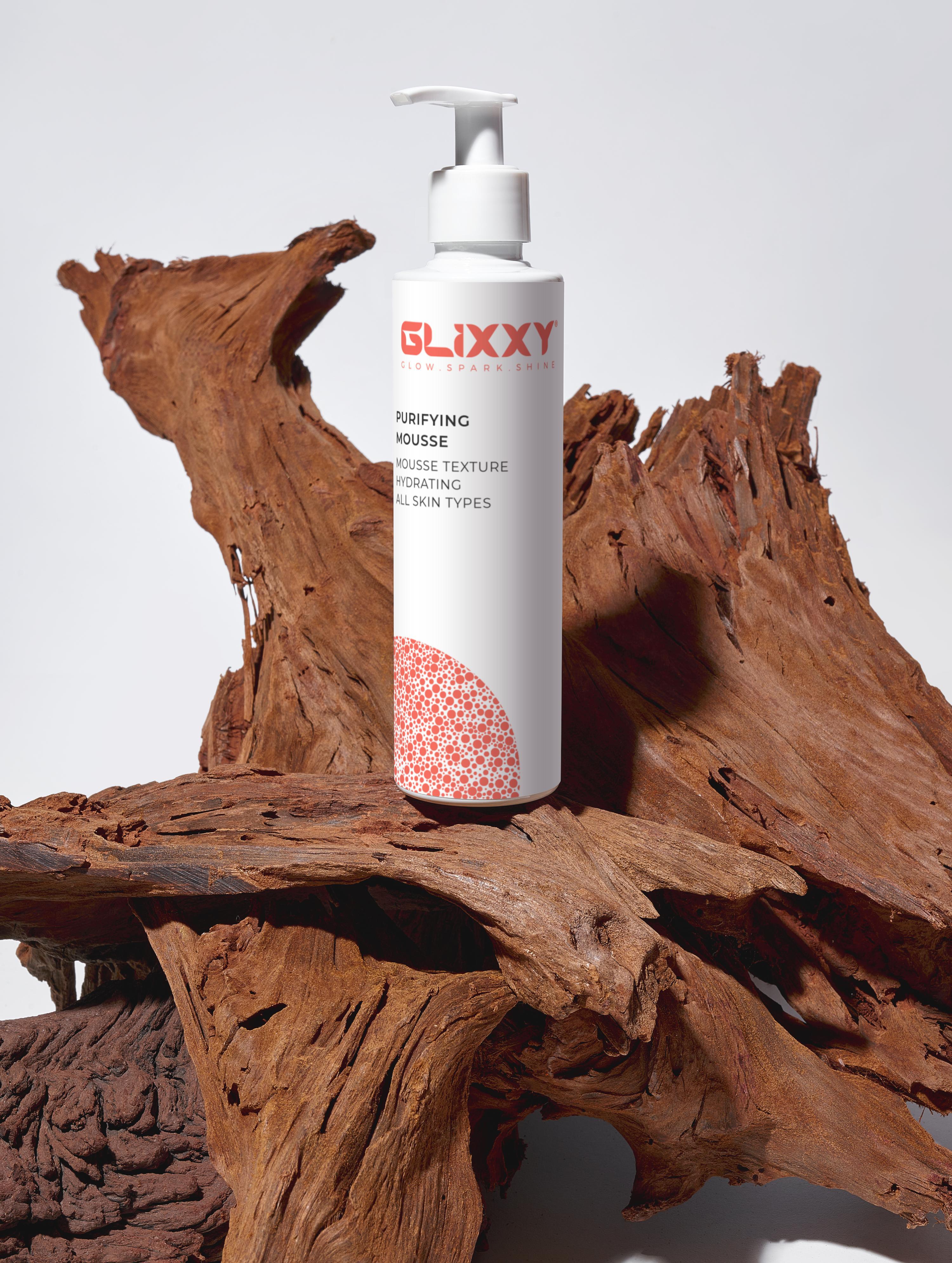 Glixxy purifying mousse bottle on a wooden surface with a white background
