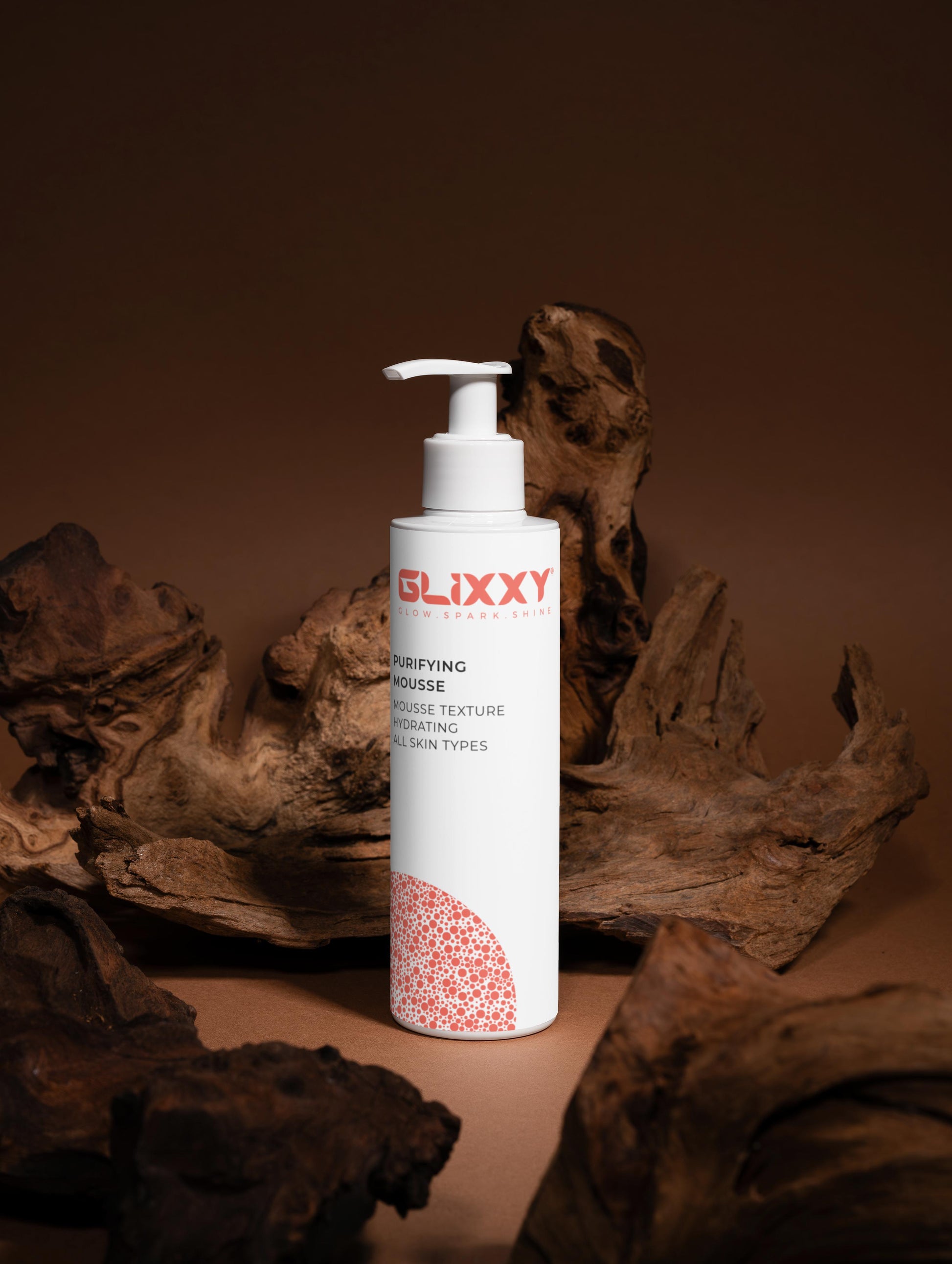 Glixxy purifying mousse product bottle on a brown background with natural elements