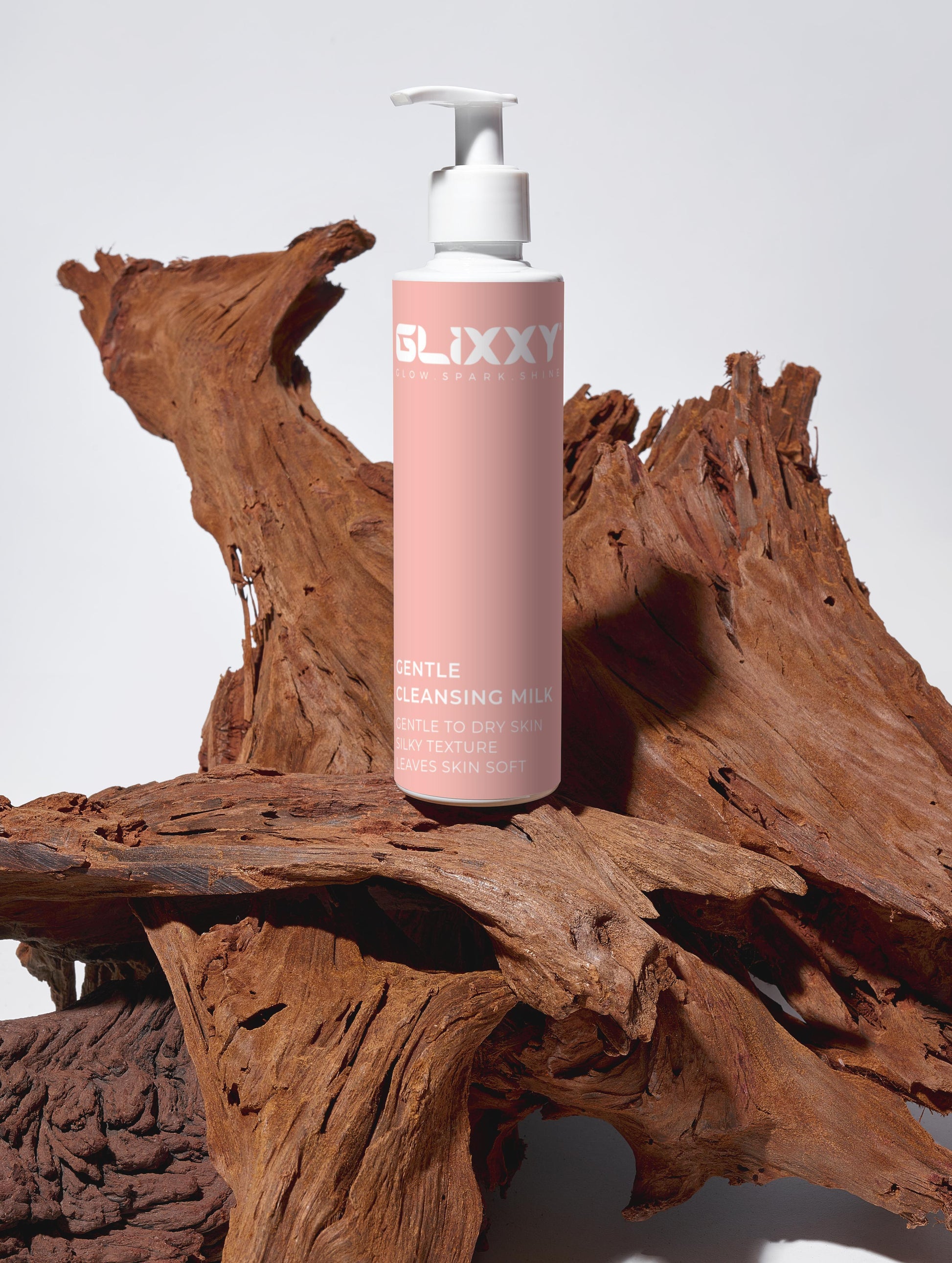 Pink bottle of Glixxy Gentle Cleansing Milk on a wooden surface
