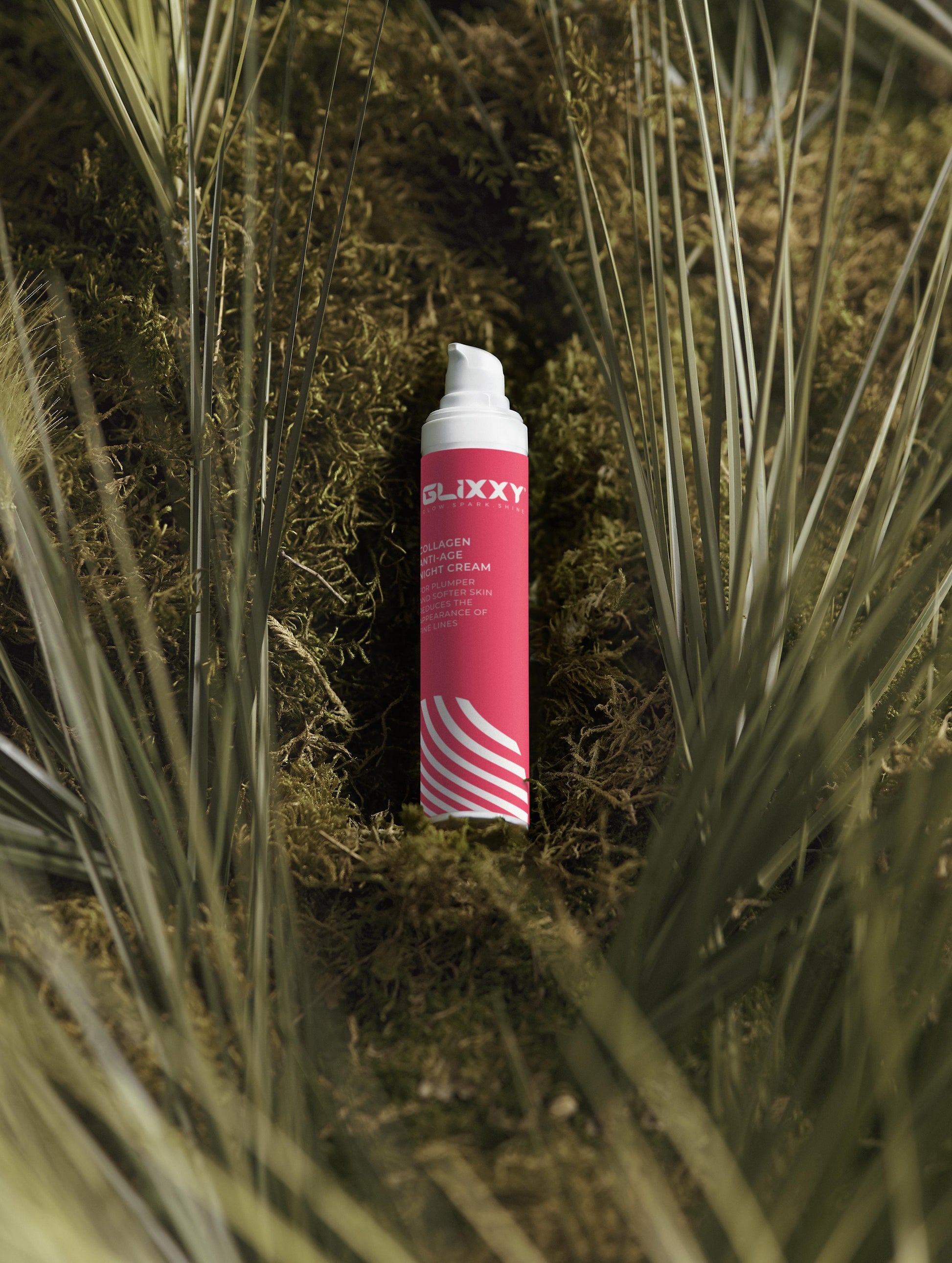Pink and white canister with 'Glixxy' branding on a grassy background