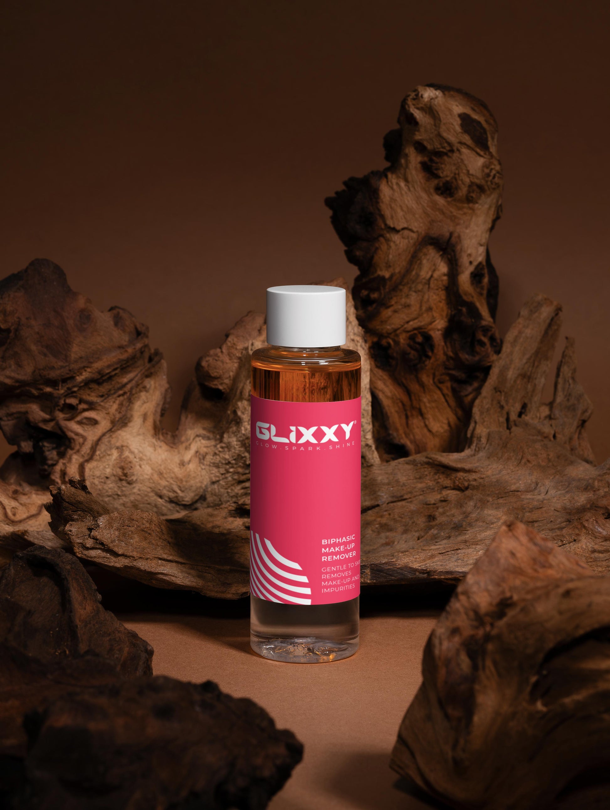 Bottle of Glixxy best make up remover product with a pink label on a brown background