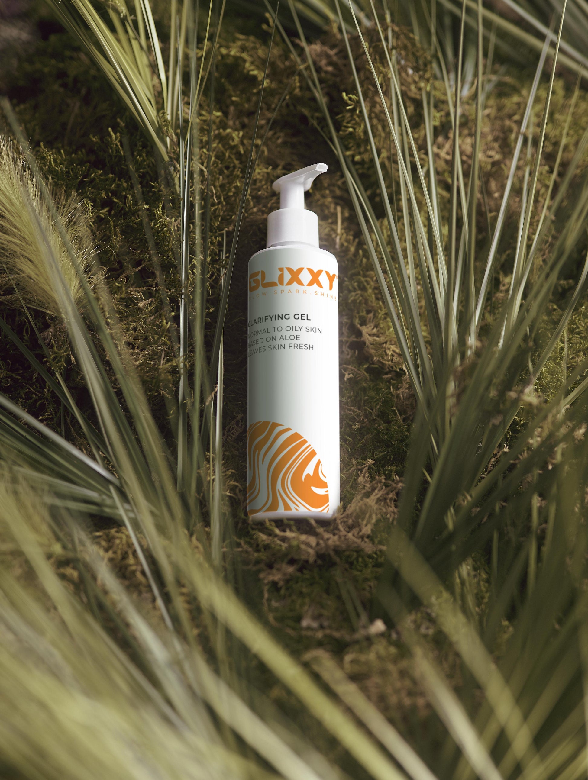 Glixxy bottle of gel in a natural setting with grass and moss
