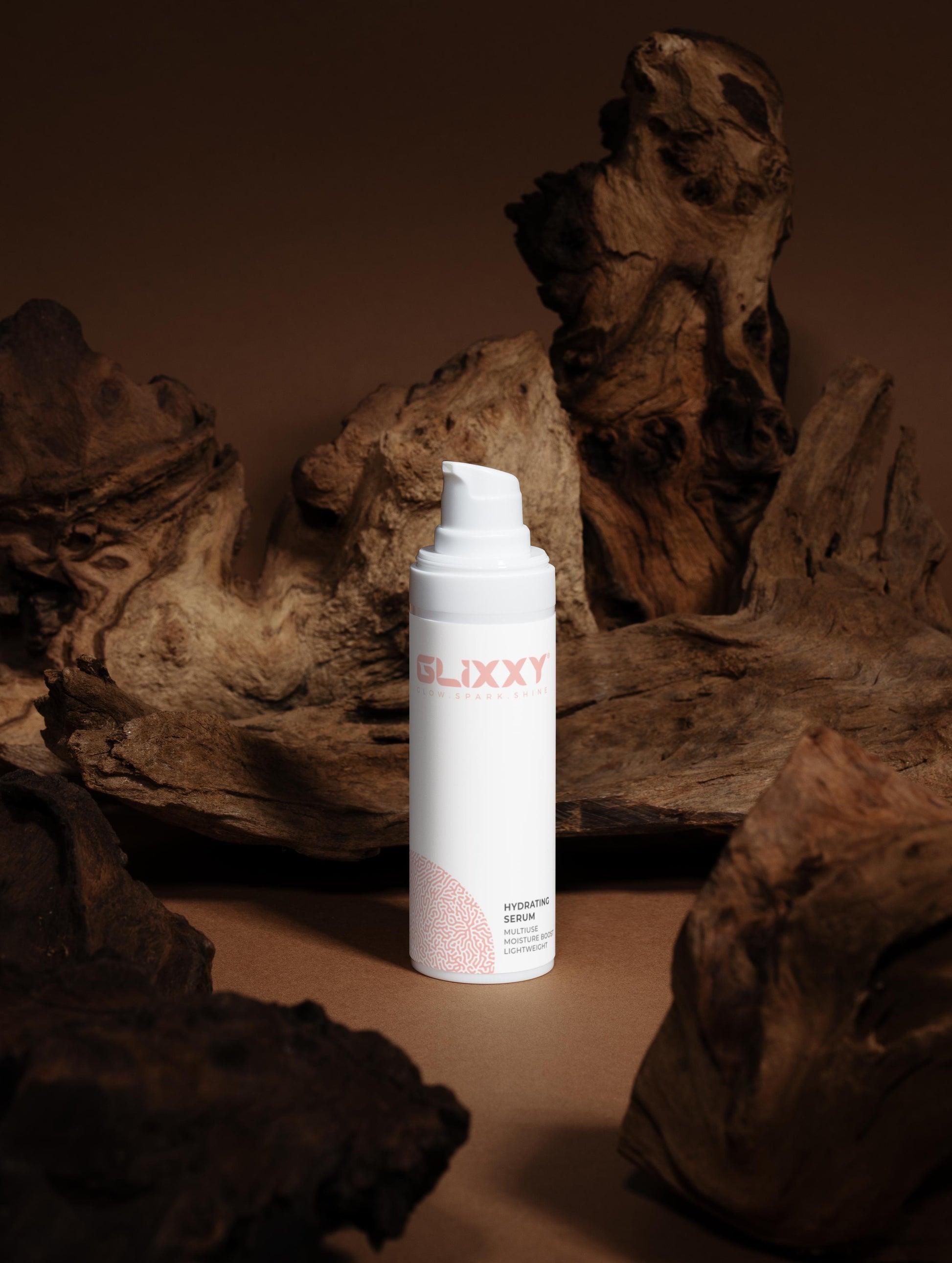 Glixxy hydrating hyaluronic acid serum bottle on a textured brown surface
