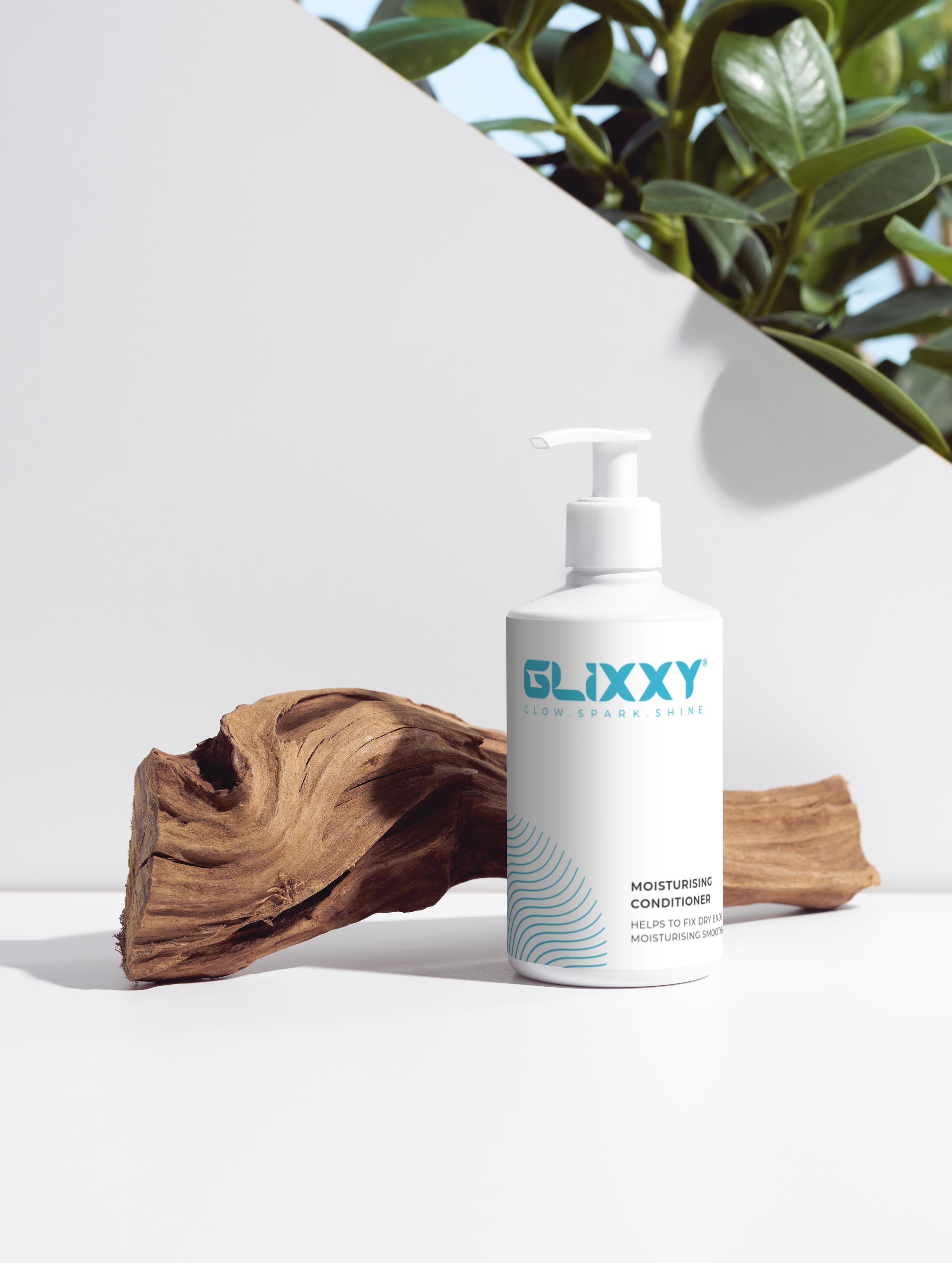 Glixxy moisturising conditioner for curly hair bottle on a white surface with a plant in the background