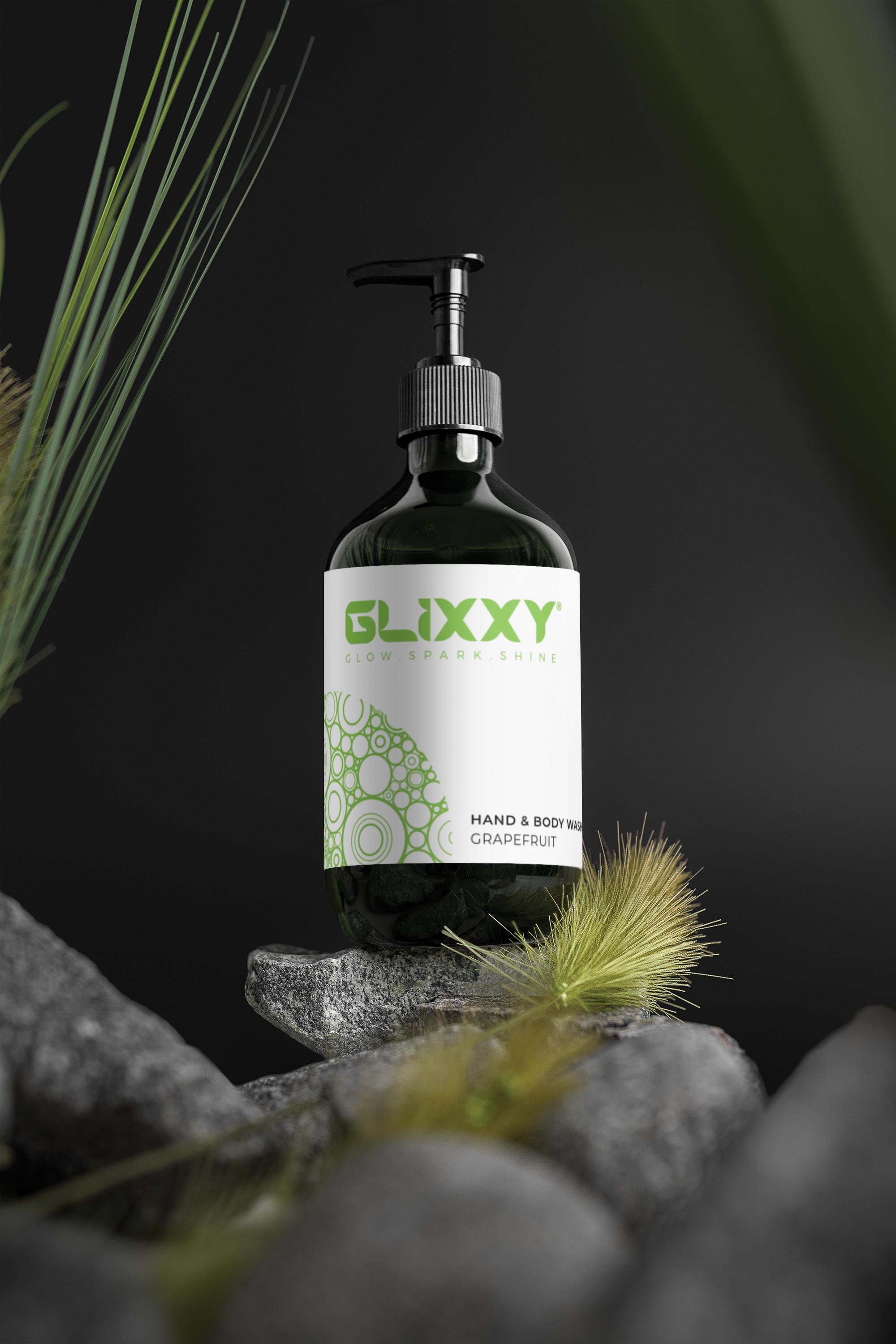 Glixxy hand and body wash bottle on a dark background with greenery