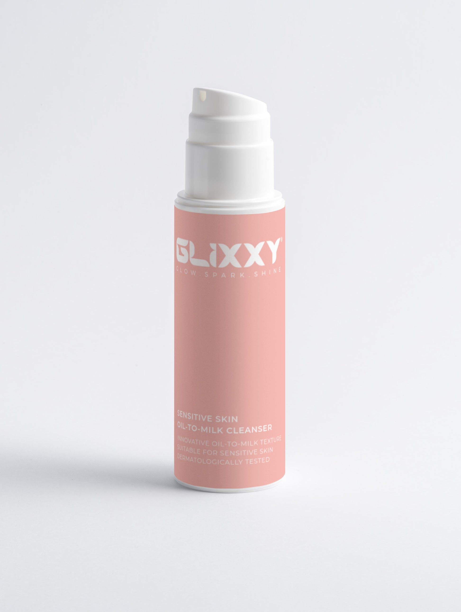 Pink skincare product bottle with white cap on a light gray background containing sensitive skin oil-to-milk cleanser