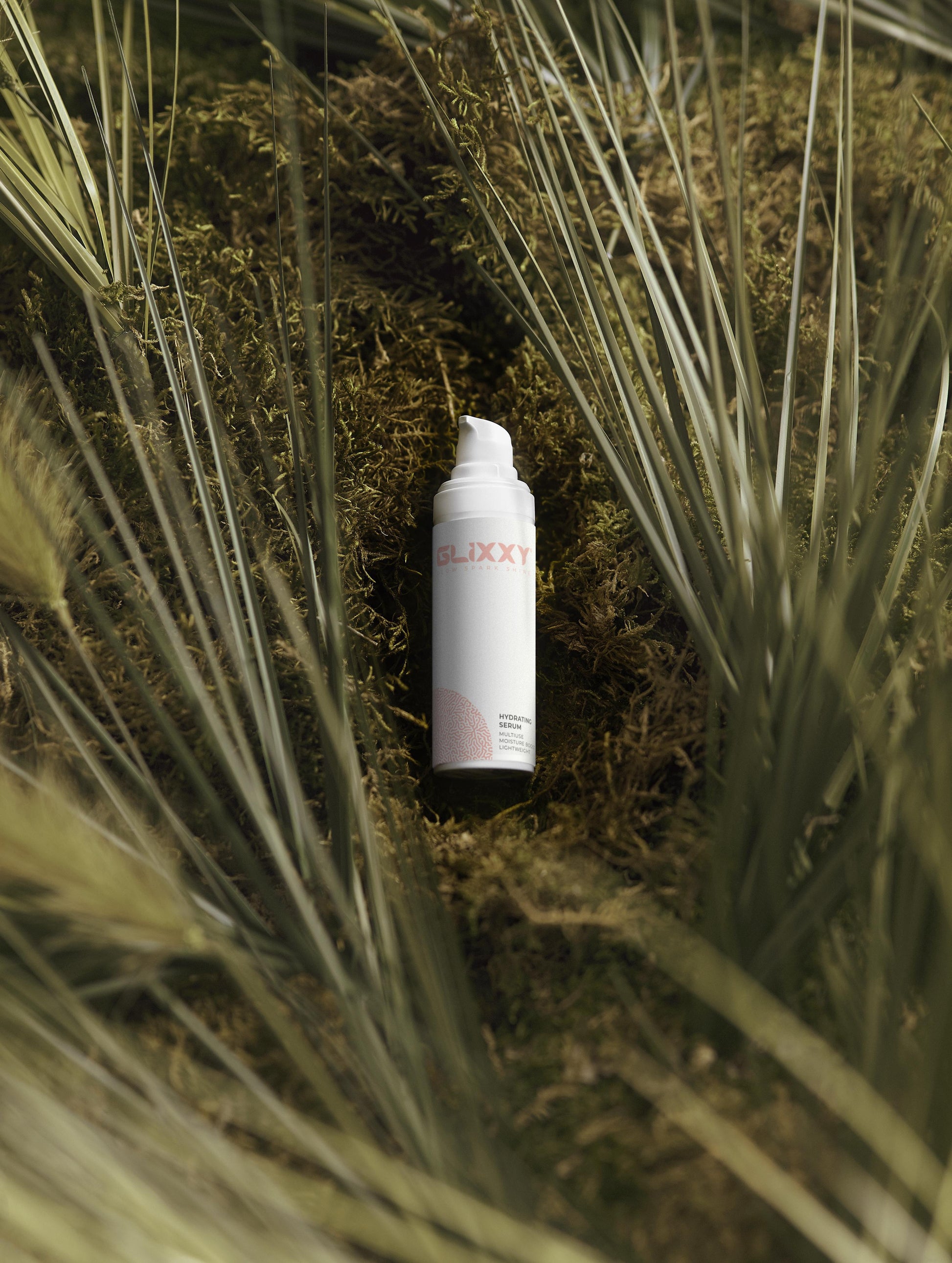 White top hydrating serums bottle with red text on a grassy background