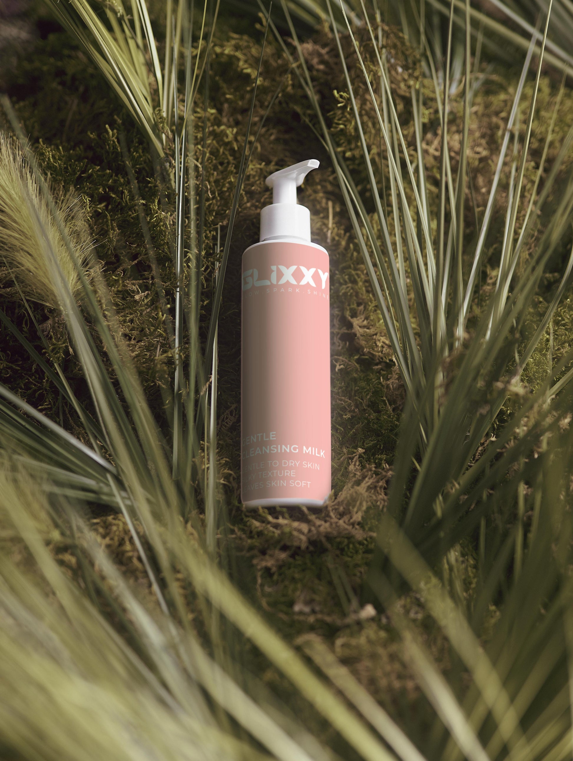 Pink bottle labeled 'Glixxy' surrounded by green plants